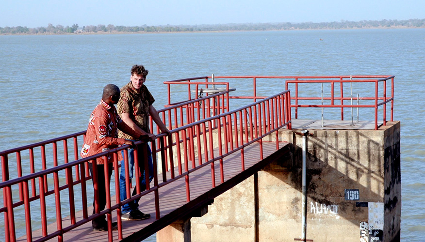 Two men standing on a platform overlooking a large body of water.