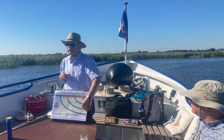 A man is showing a sheet while standing in front of a boat.