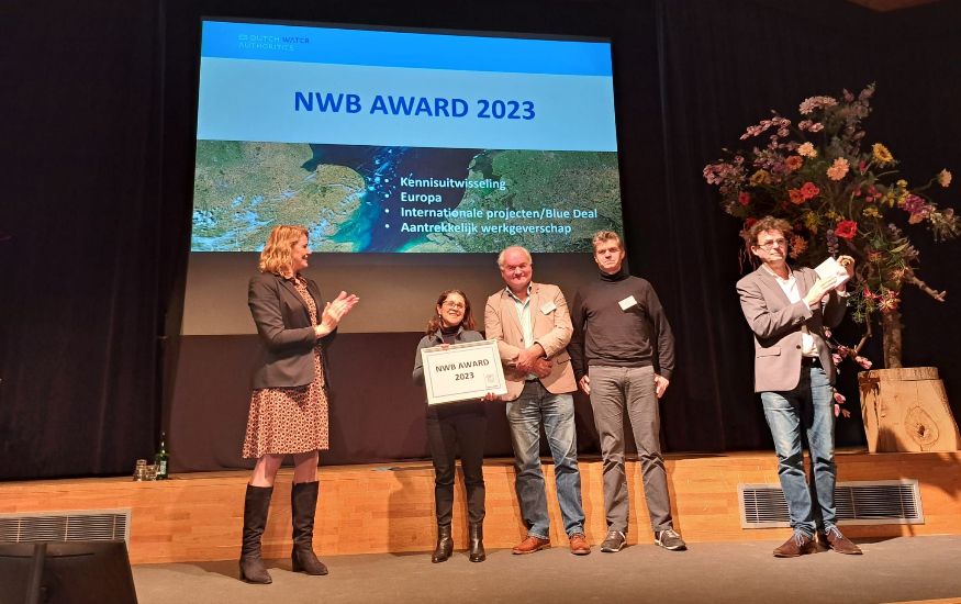 5 persons are standing on stage before a presentation with the words NWB Award 2023.