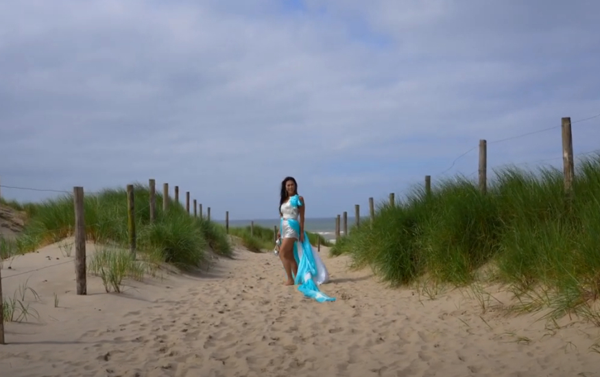 A woman is standing in the middle of a sandy road at the dunes