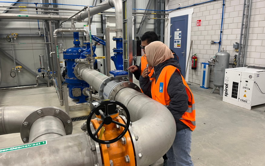 2 people are looking at the tubes inside a wastewater treatment plant